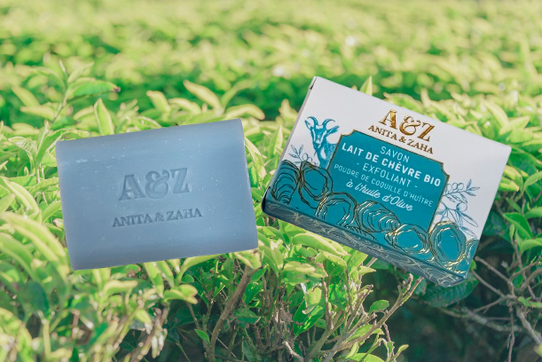 Photo du Savon Exfoliant au lait de chèvre bio et à la poudre de coquille d'huître ANITA & ZAHA, posé devant des plantes de thé- ANITA & ZAHA ©