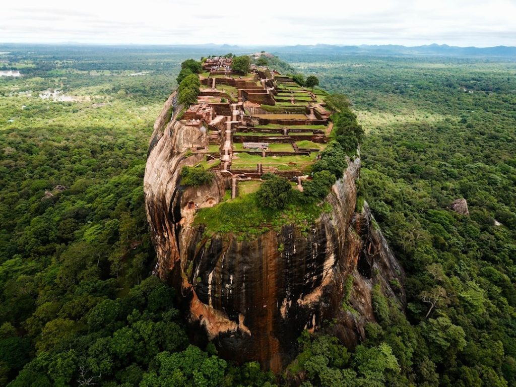 Vue panoramique du rocher de Sigirîya au Sri Lanka, imposante formation rocheuse historique entourée de végétation luxuriante.