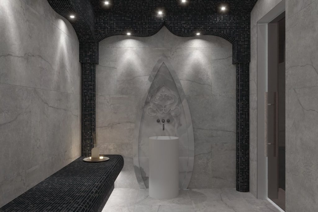 Hammam moderne individuel en marbre avec zone de gommage et point d’eau.